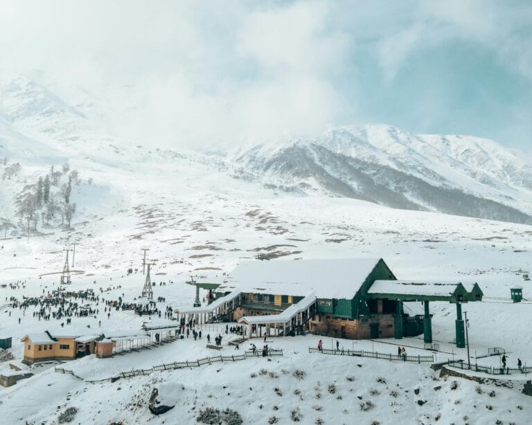 Aerial view of Gulmarg resort with snowy mountains, perfect winter travel destination.
